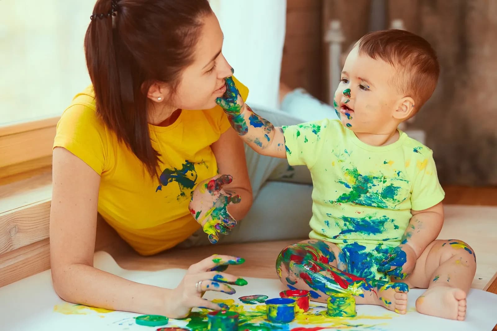 a woman and baby with paint on their hands