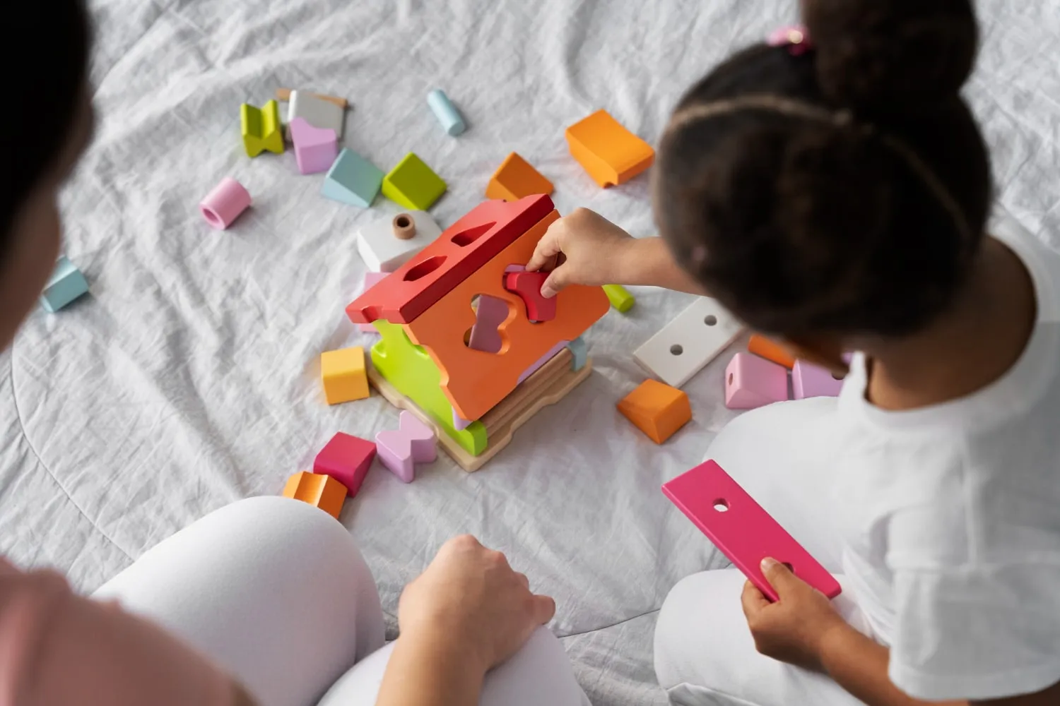 Children sorting colourful shapes into a wooden toy
