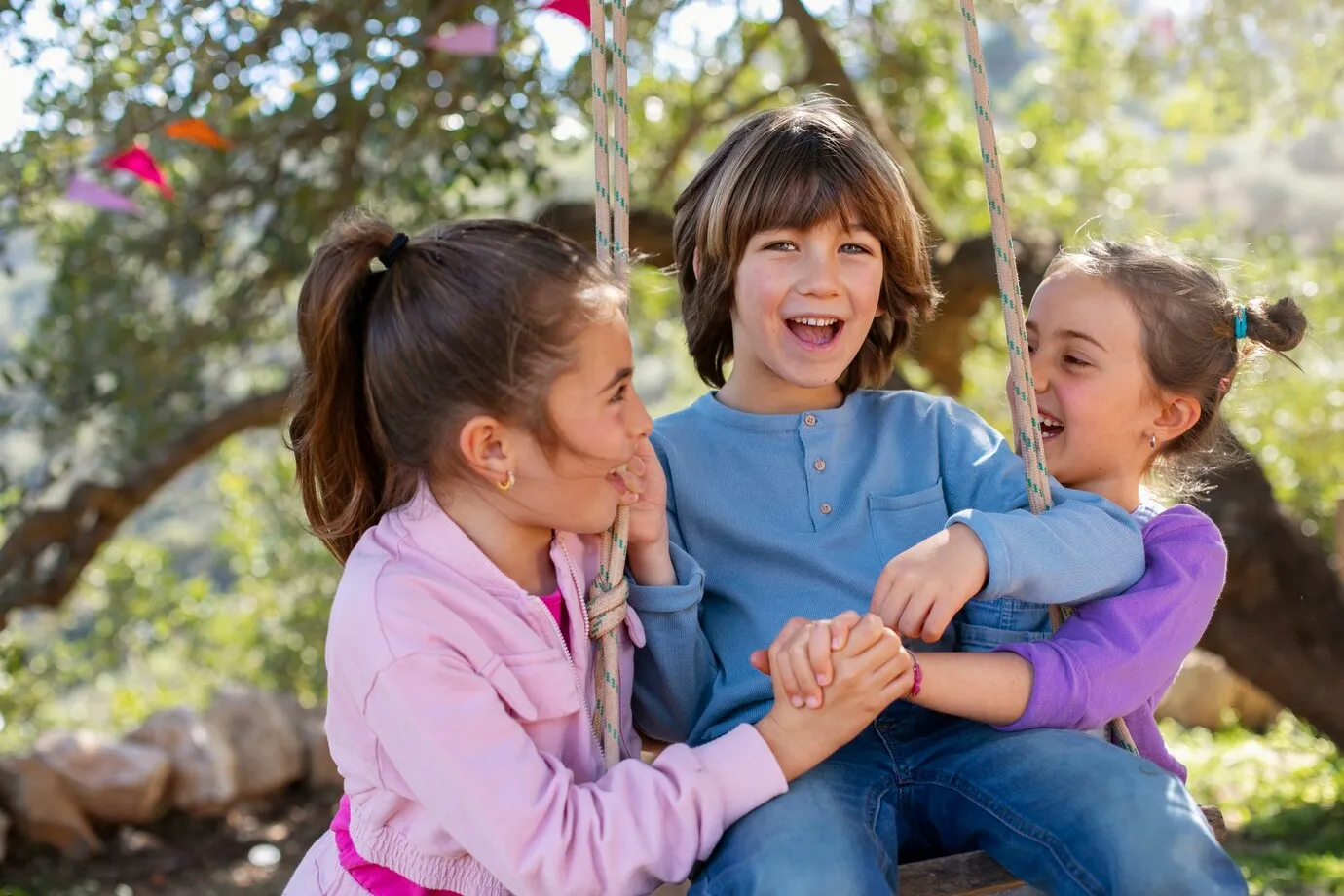 Three children smiling and playing together outdoors