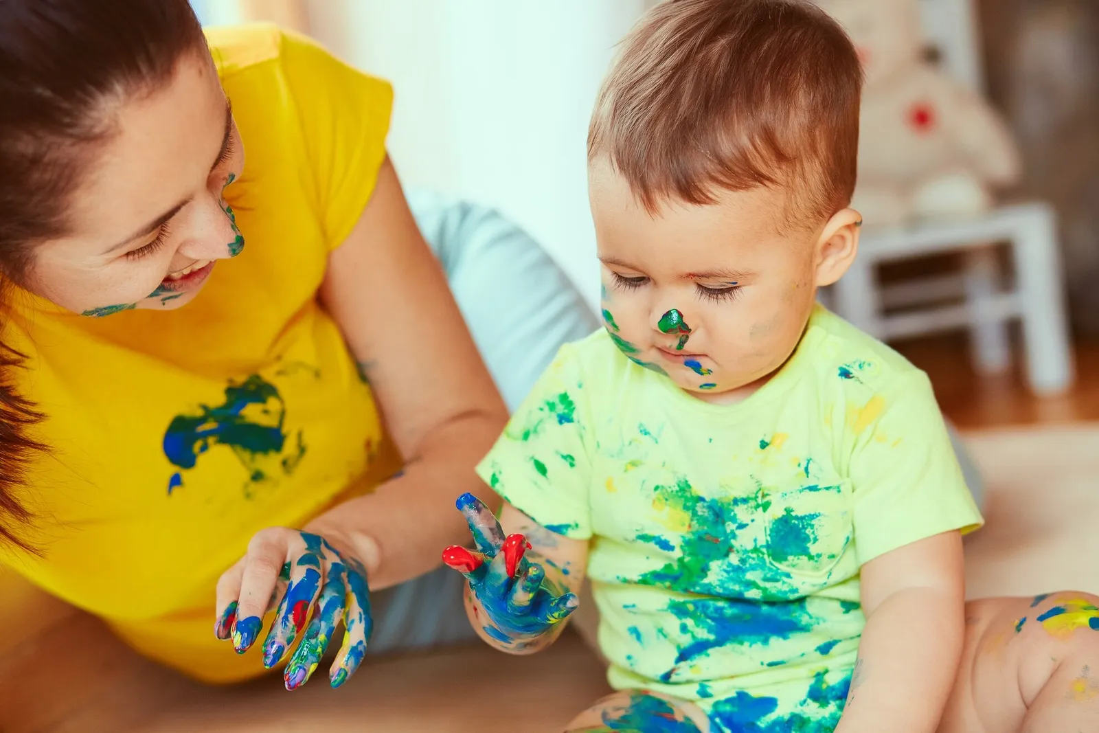 An adult helping a toddler with a painting activity