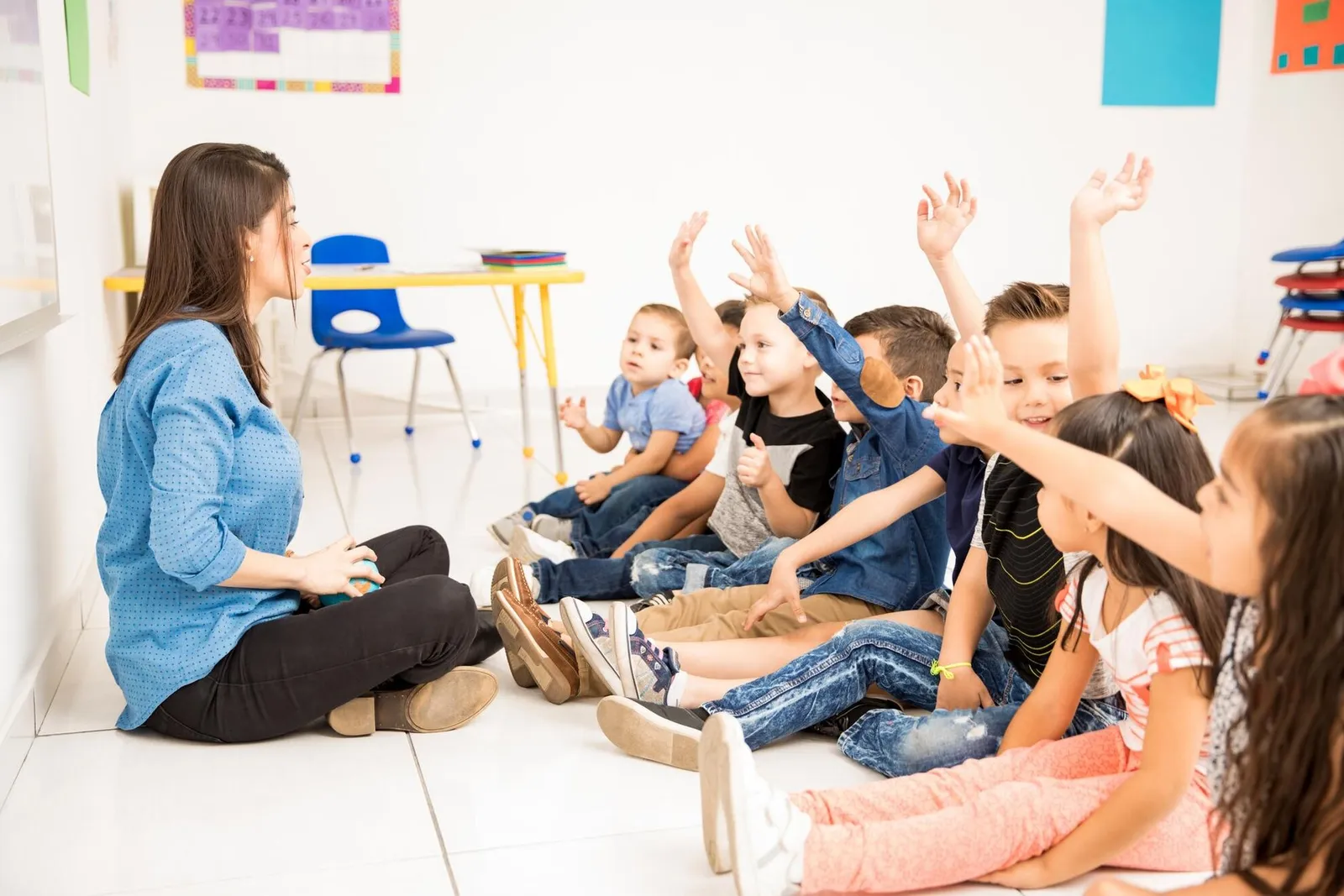 A teacher asking a question as children raise their hands